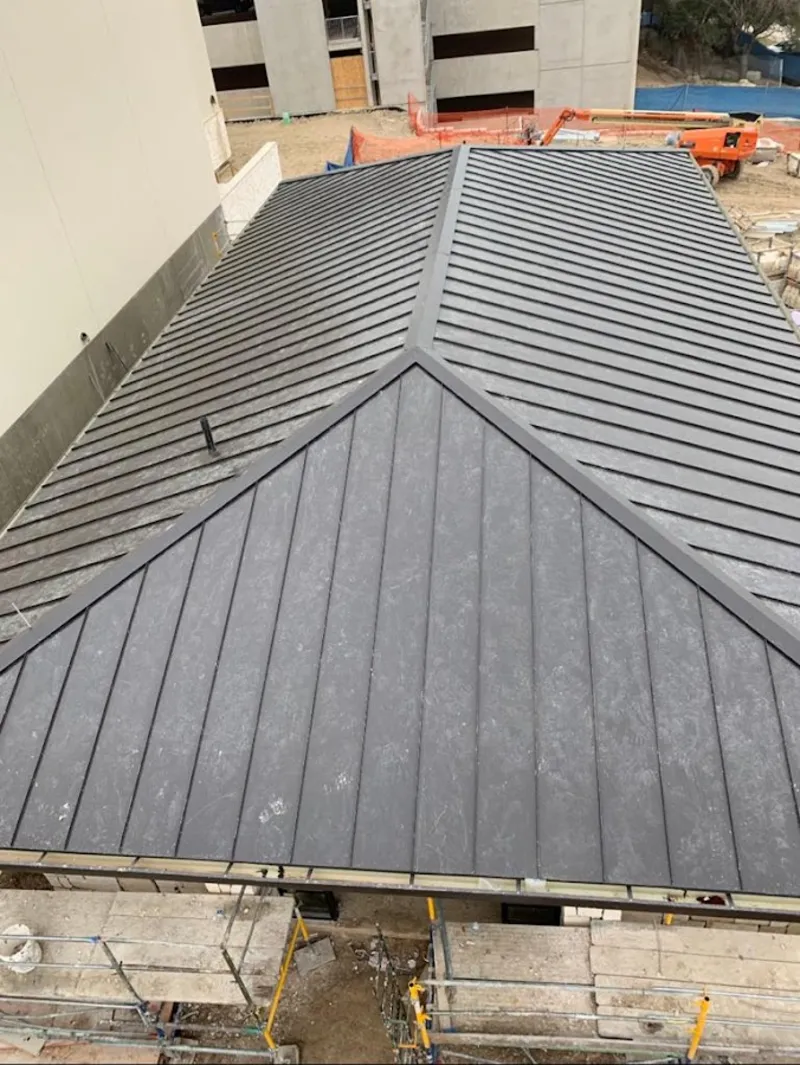 Commercial metal roof construction with crane equipment in Milford